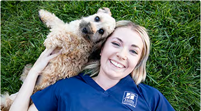 Frau liegt mit einem Hund im Gras